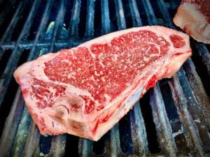 Strip Steak on the grill with salt and pepper