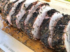 Sliced Pork Tenderloin herb Crusted on cutting board