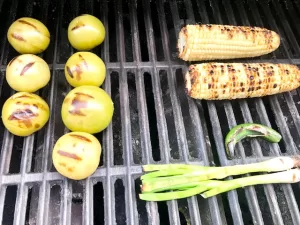 Grilled Corn, Tomatillos, Serrano Pepper, and Green Onions on grill grates with Sear Marks