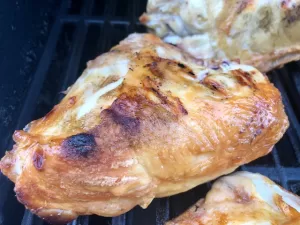 Grilled Chicken Breast Bone In with skin on sitting on grill grates