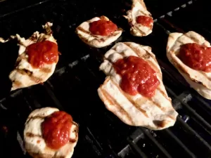 Grilled Chicken with red sauce sitting on grill grates