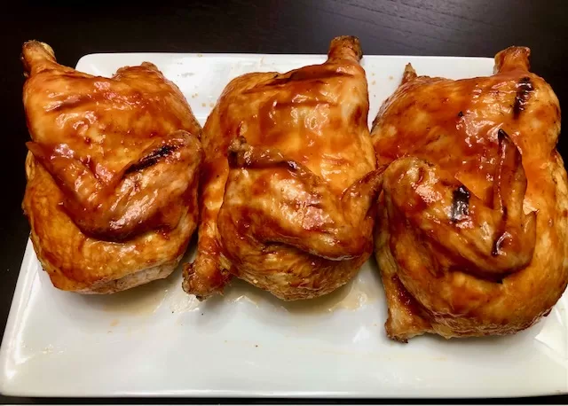 Three Half chickens plated with apple cider BBQ sauce