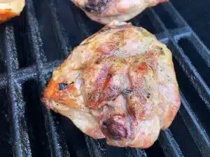 Chicken thigh laying skin side down on grill grates