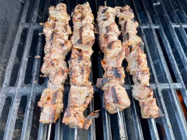 Shallot Sauce Grilled Beef that are skewered and laying on grill grates.