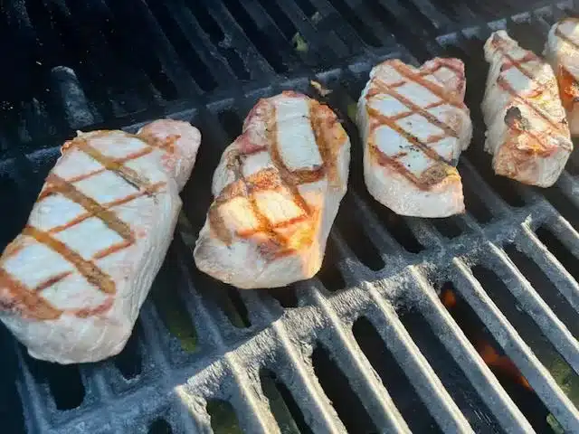 Juicy Boneless Pork Chops sitting on grill grates with searmarks